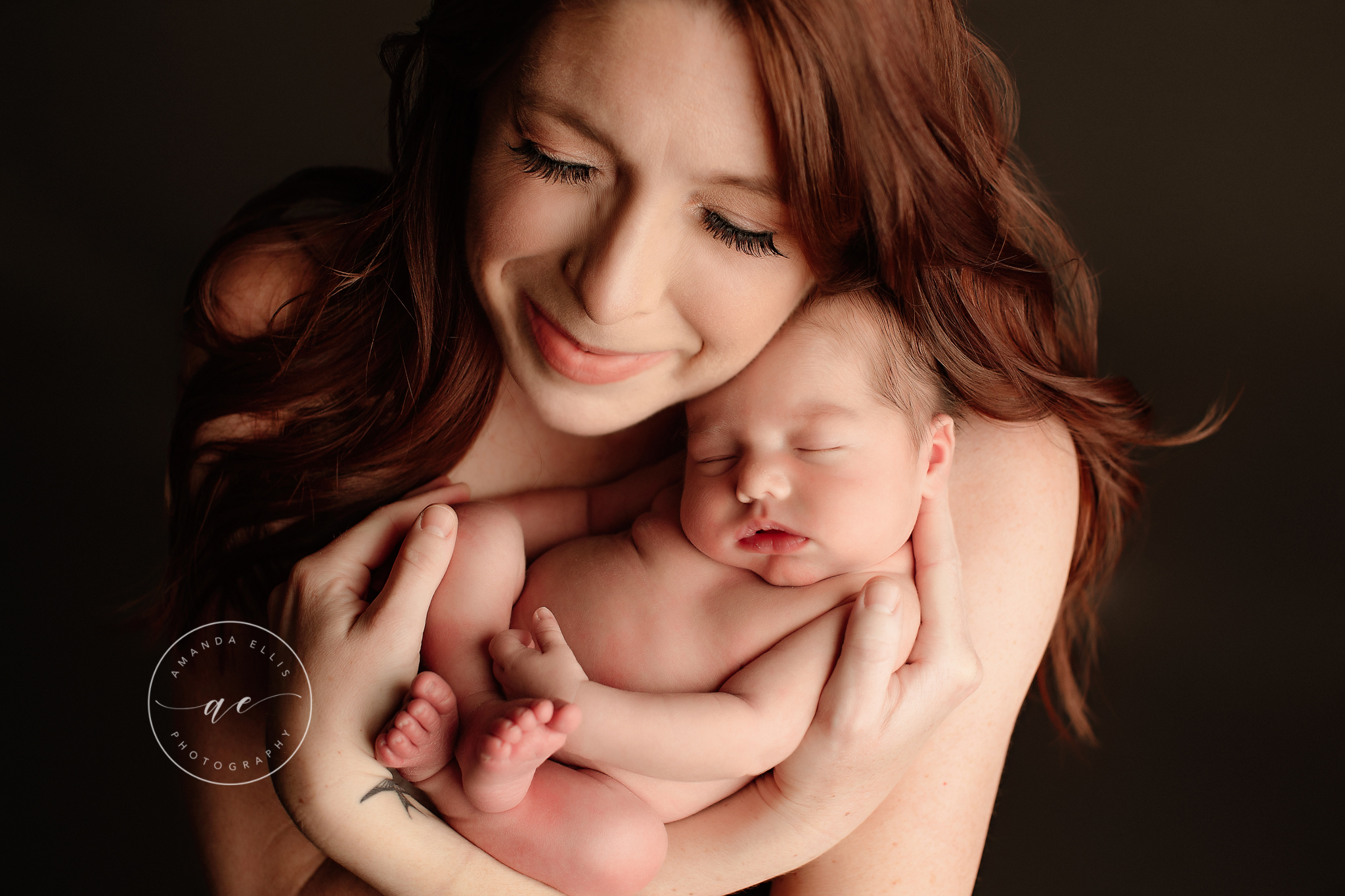 Mother with long red hair smiling sweetly at her new baby