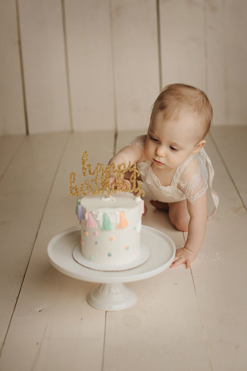 Baby playing with cake during their cake smash portraits.