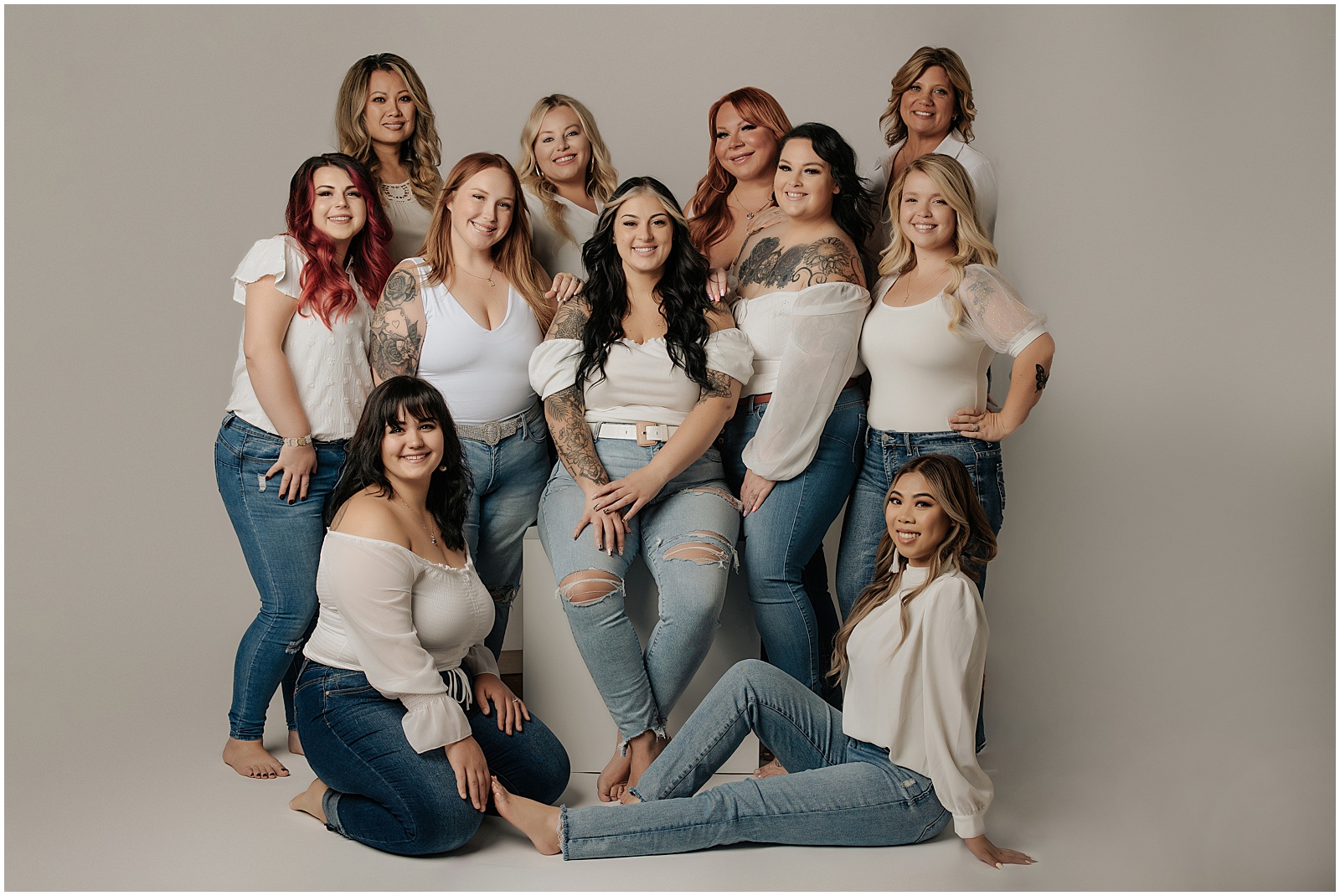 Image of a group of women all wearing a white shirt and blue jeans smiling at the camera | Team Headshots by Amanda Ellis Photography